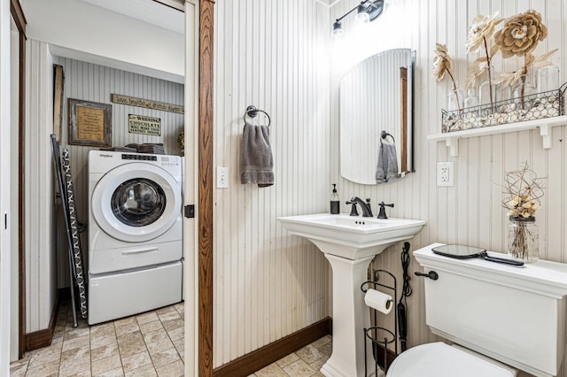 bathroom featuring toilet, stone finish floor, a sink, and washer / dryer