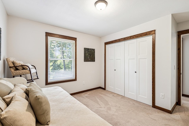 bedroom featuring light carpet, baseboards, and a closet