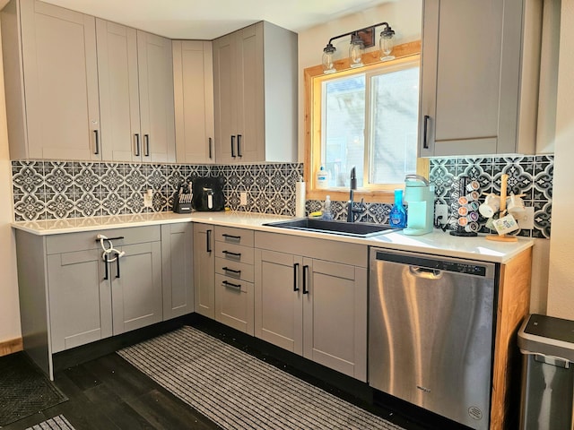 kitchen featuring gray cabinets, dark hardwood / wood-style flooring, stainless steel dishwasher, and sink