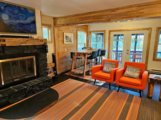 living room with french doors, a stone fireplace, baseboard heating, and a wealth of natural light