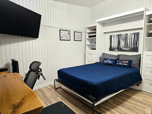 bedroom with wood walls and light hardwood / wood-style flooring