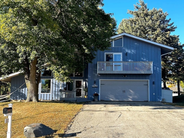 view of front facade featuring a balcony, a front yard, and a garage