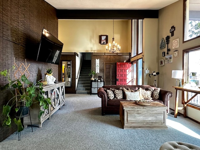 living room featuring beam ceiling, carpet floors, and an inviting chandelier