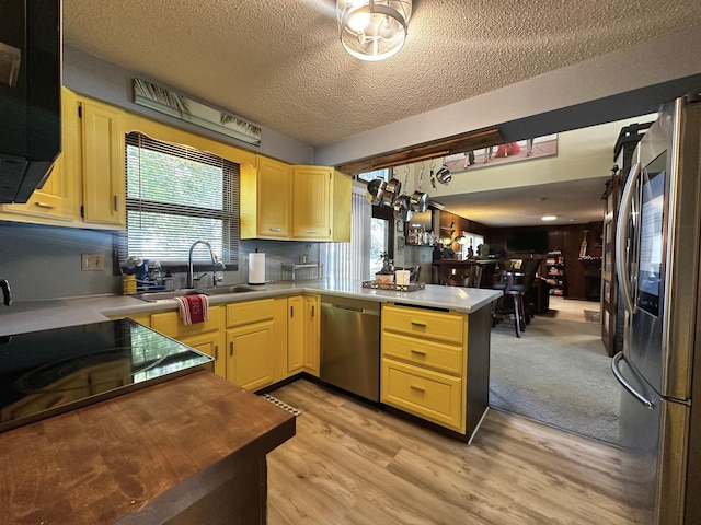 kitchen with light hardwood / wood-style floors, stainless steel appliances, a textured ceiling, and plenty of natural light