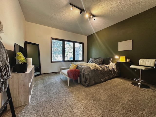 bedroom featuring track lighting, a textured ceiling, and carpet flooring