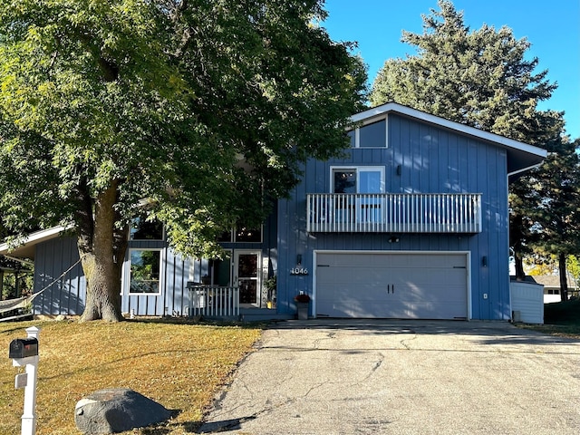 view of front of home with a balcony, a front yard, and a garage