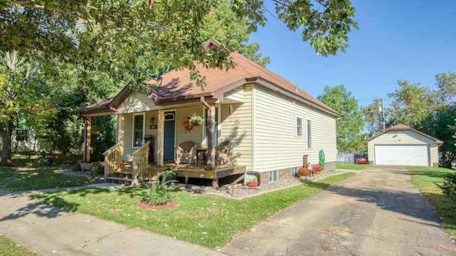 bungalow featuring a front lawn, an outbuilding, a detached garage, and covered porch