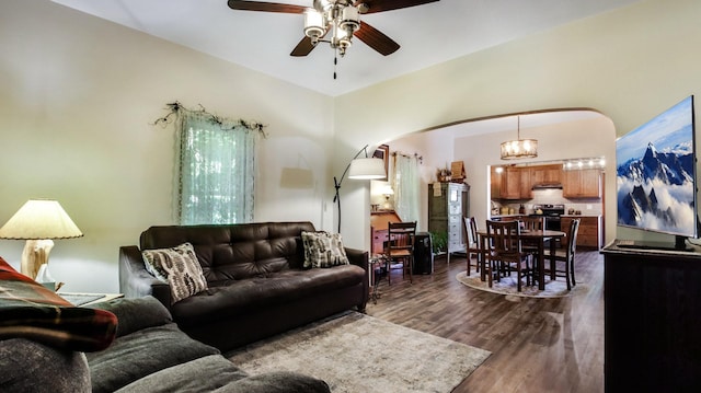 living area featuring arched walkways, dark wood finished floors, and a ceiling fan