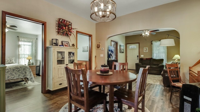 dining room featuring dark wood finished floors, arched walkways, and ceiling fan with notable chandelier