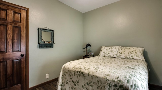 bedroom featuring lofted ceiling, baseboards, and dark wood finished floors