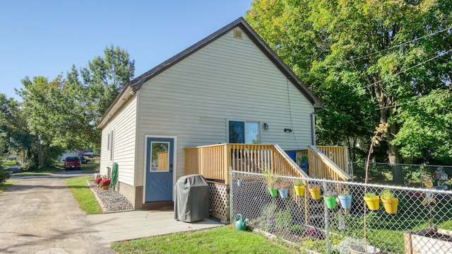 rear view of house with driveway, fence, and a deck