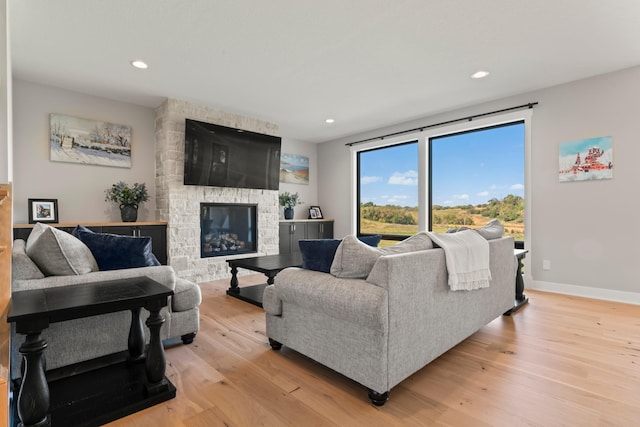 living room with light hardwood / wood-style floors and a stone fireplace