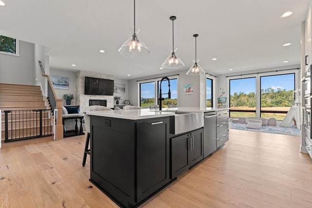 kitchen with light hardwood / wood-style flooring, a fireplace, and a kitchen island with sink