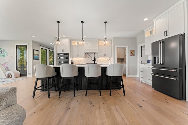 kitchen featuring a center island with sink, light hardwood / wood-style floors, high quality fridge, and white cabinetry