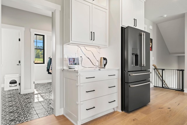 kitchen featuring light wood-type flooring, high quality fridge, vaulted ceiling, and white cabinets