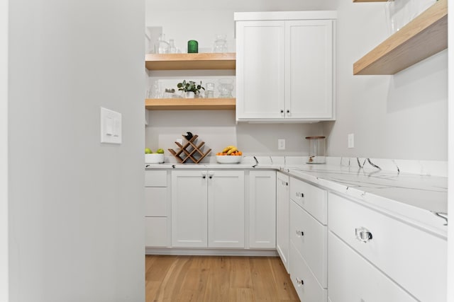 kitchen featuring light hardwood / wood-style flooring, white cabinets, and light stone counters