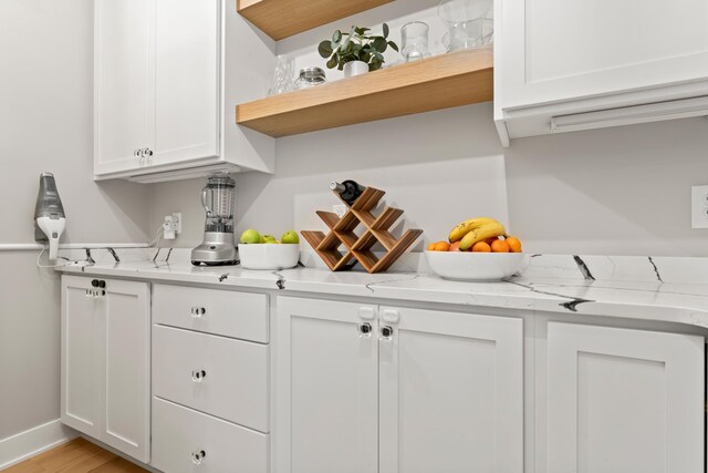 interior space featuring light stone counters, light wood-type flooring, and white cabinetry