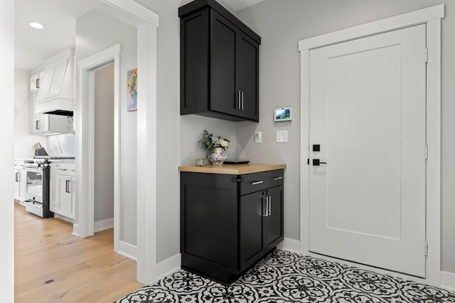 interior space with light wood-type flooring, stainless steel gas stove, and wood counters