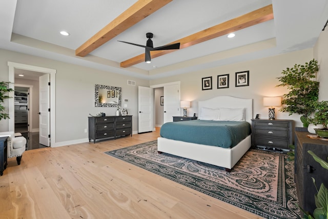 bedroom with ceiling fan, a tray ceiling, beam ceiling, and hardwood / wood-style floors