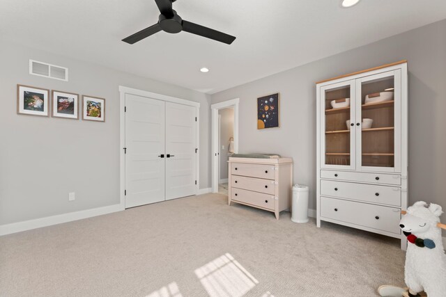 unfurnished bedroom with ceiling fan, light colored carpet, and a closet