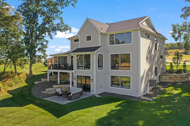 rear view of property featuring a lawn, a patio, and central AC