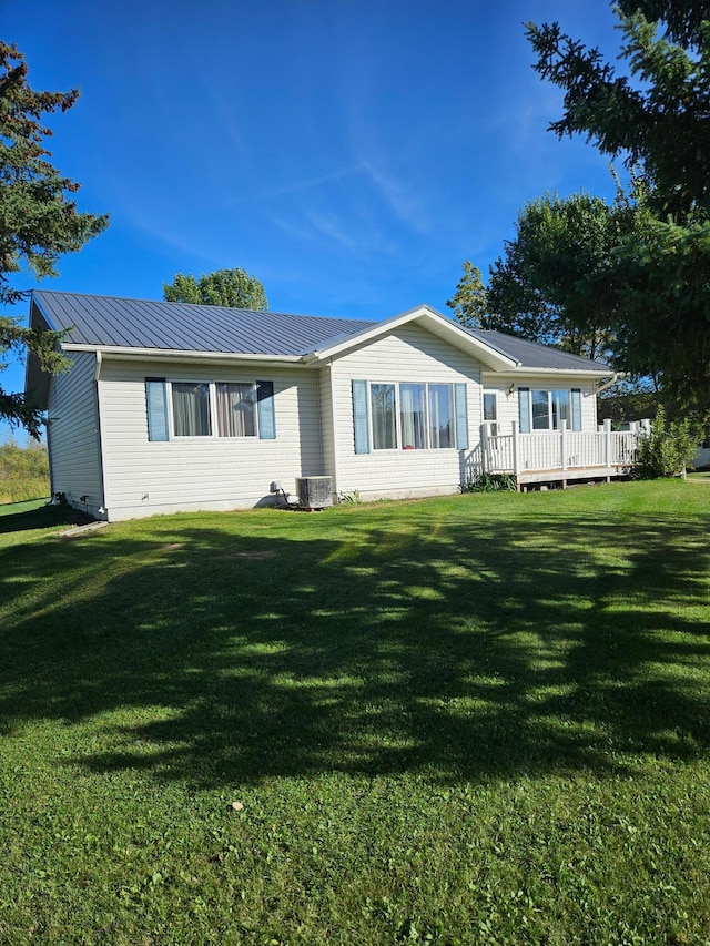 back of property featuring a deck, a yard, and central AC unit