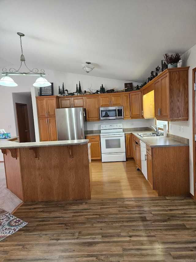 kitchen featuring dark hardwood / wood-style flooring, appliances with stainless steel finishes, a kitchen bar, vaulted ceiling, and decorative light fixtures