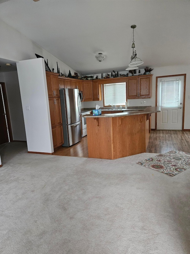 kitchen with stainless steel fridge, a center island, decorative light fixtures, and light wood-type flooring