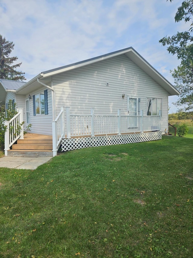 rear view of house with a wooden deck and a yard