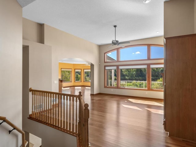 living room featuring light wood-type flooring, ceiling fan, and a textured ceiling