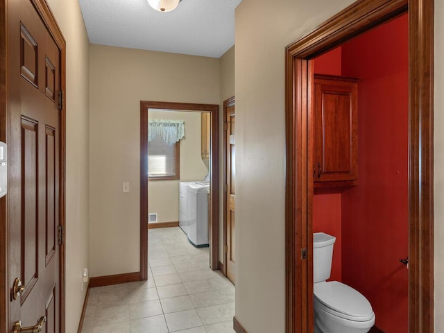 bathroom with toilet, washing machine and clothes dryer, and tile patterned floors