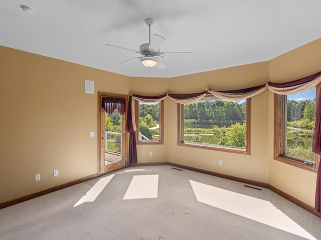 empty room featuring ceiling fan and light carpet