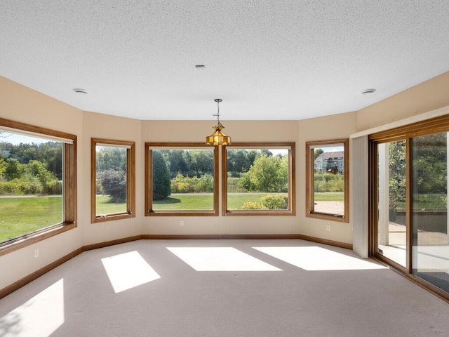 carpeted spare room featuring a wealth of natural light and a textured ceiling