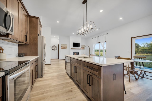 kitchen with a breakfast bar, a kitchen island with sink, sink, light hardwood / wood-style flooring, and stainless steel appliances