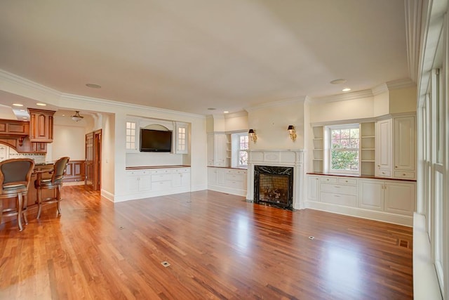 living room with a fireplace, light wood-type flooring, and crown molding