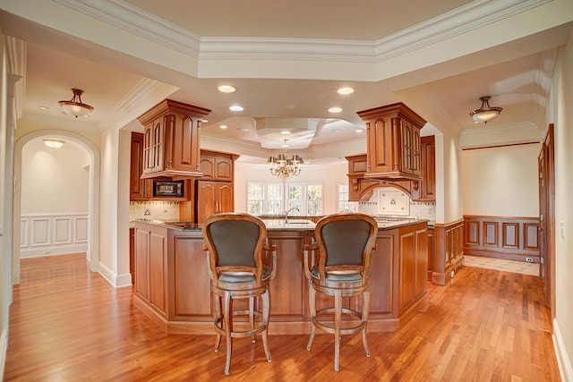 kitchen with light wood-type flooring, backsplash, ornamental molding, sink, and a chandelier