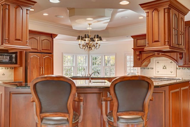 kitchen featuring light stone counters, ornamental molding, sink, and an inviting chandelier