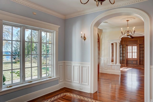 interior space with wood-type flooring, ornamental molding, and an inviting chandelier