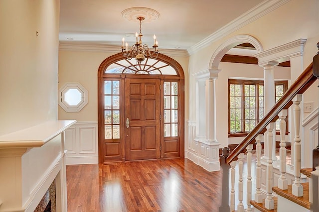 foyer entrance featuring hardwood / wood-style flooring, plenty of natural light, crown molding, and a notable chandelier