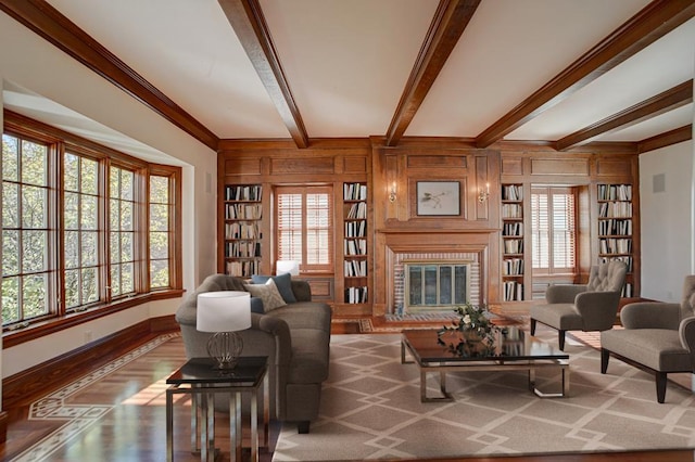 living room featuring beamed ceiling, ornamental molding, hardwood / wood-style flooring, and a brick fireplace