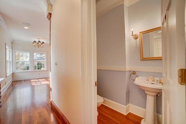 bathroom featuring wood-type flooring, an inviting chandelier, toilet, and crown molding