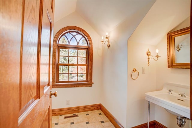 bathroom with plenty of natural light, lofted ceiling, and sink