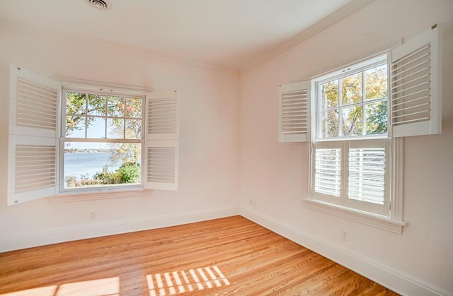 empty room with light hardwood / wood-style floors and crown molding