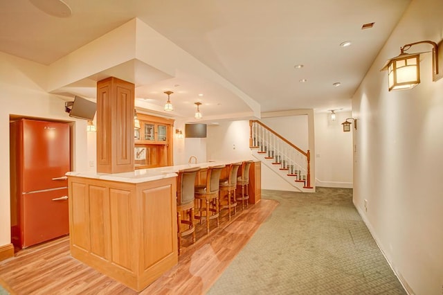 kitchen featuring a kitchen breakfast bar, a kitchen island, and light hardwood / wood-style flooring