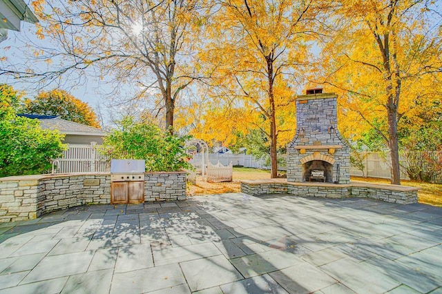 view of patio / terrace with an outdoor stone fireplace and an outdoor kitchen