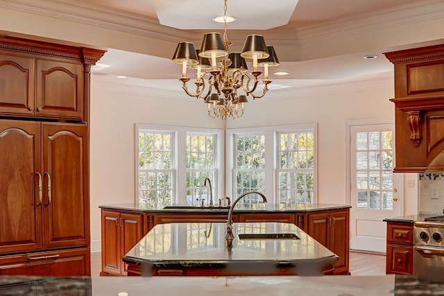 kitchen featuring decorative light fixtures, tasteful backsplash, an island with sink, high end stainless steel range oven, and ornamental molding