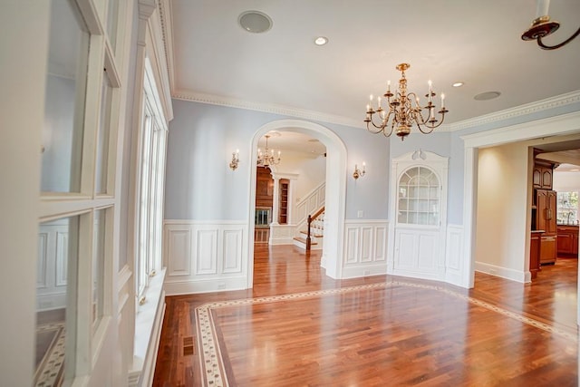 unfurnished dining area featuring ornamental molding, hardwood / wood-style floors, and a notable chandelier