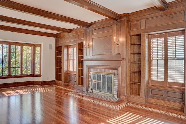 unfurnished living room with built in shelves, wood-type flooring, and beamed ceiling