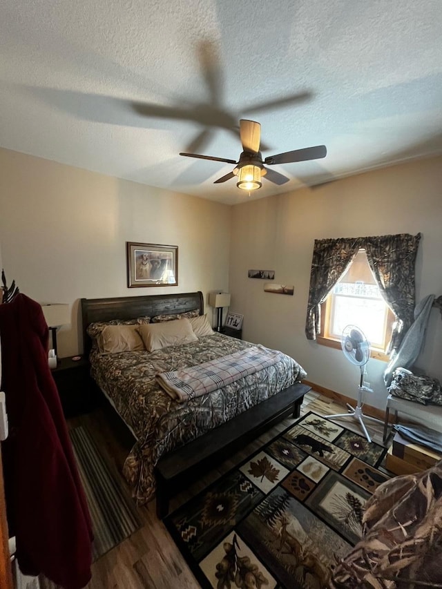 bedroom with ceiling fan, a textured ceiling, and hardwood / wood-style floors