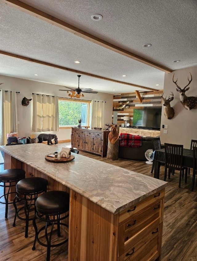 kitchen with ceiling fan, a textured ceiling, beam ceiling, and dark wood-type flooring